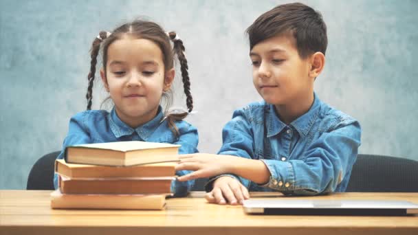 Duas crianças escolhendo entre pilha de livros e laptop. Laptop é o vencedor . — Vídeo de Stock