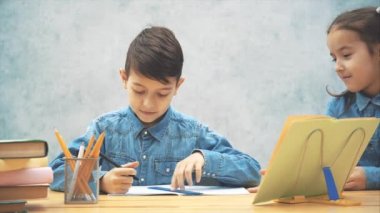 Konsantre okul çocuğu cetvel ile bir şey vurguluyor, sonra kız kardeşi geliyor, cetvel almak isteyen, güzel yüz ifadesi ile bakarak, ama kardeşi onu uzağa yapar.
