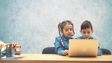 Sevimli küçük okul çocukları masada oturan, internette arama, dizüstü bilgisayar, ve buldukları bir şey memnun.