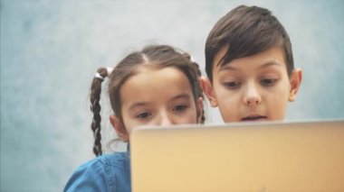Sevimli küçük okul çocukları masada oturan, internette arama, dizüstü bilgisayar.