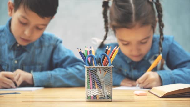 小学生、兄弟姉妹のぼやけた作物、テーブルに座って、書き、そして彼らが書いたものを互いに示す. — ストック動画