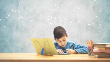 Mavi kot t-shirt yazma genç konsantre okul çocuk, kitap sahibi üzerinde kitaptan metin kopyalama.