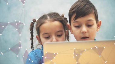 Sevimli küçük okul çocukları masada oturan, internette arama, dizüstü bilgisayar, ve buldukları bir şey memnun.