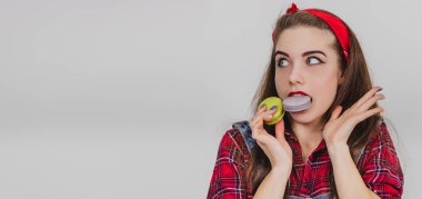 Neşeli, çocuksu kız elinde tatlı kurabiyelerle kameraya bakıyor. Gözleri kocaman açılmış..