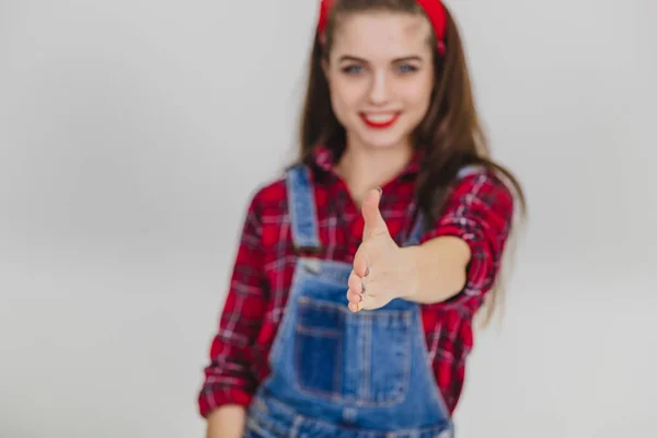 Borrado bonito jovem sorrindo mulher estendendo a mão para a câmera, querendo agitá-lo com alguém, saudação . — Fotografia de Stock