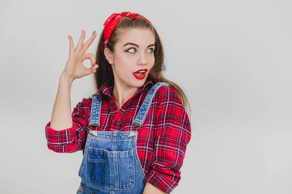 Retrato de um bonito animado menina no xadrez camisa mostrando ok gesto e sorrindo . — Fotografia de Stock