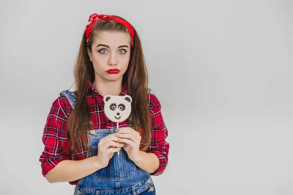 Engraçado jovem de pé com delicioso panda-pirulito na mão, olhando ofendido e chateado . — Fotografia de Stock