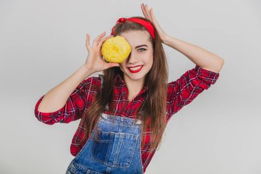 Güzel genç bayan, sarı kremalı ve gülümseyen büyük çöreğin arkasına saklanıyor..