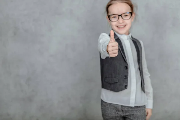 Small business lady on a gray background. Dressed in black glasses and business clothes. Large blurry background.
