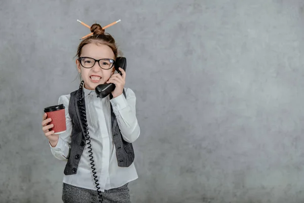 Η εικόνα των συναισθηματικών χαρούμενων προσώπων. Μικρό κορίτσι των επιχειρήσεων σχολείο κορίτσι. Χαμογελώντας και μιλώντας με το τηλέφωνο και κρατώντας καφέ. Η έννοια της επιχειρηματικής επικοινωνίας. — Φωτογραφία Αρχείου