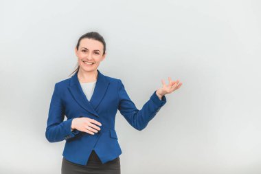 Güzel genç öğretmen ayakta duruyor, avuç içi açık bir şekilde sanki elinde bir şeyler tutuyormuş gibi, güzel gülümsüyor..