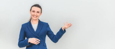 Güzel genç öğretmen ayakta duruyor, avuç içi açık bir şekilde sanki elinde bir şeyler tutuyormuş gibi, güzel gülümsüyor..
