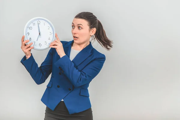 Divertido joven profesor en traje formal sosteniendo un reloj blanco, mirándolo con expresión de cara asustada . —  Fotos de Stock