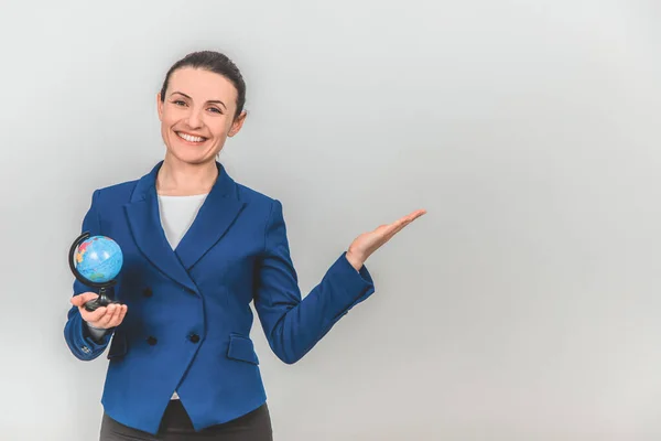 Beautiful young geography teacher with globe in one hand, pointing at the copyspace for text or product on the side, smiling. — Stock Photo, Image
