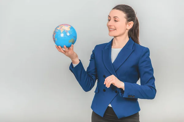 Young geography teacher holding a globe, looking at it, smiling. — Stock Photo, Image