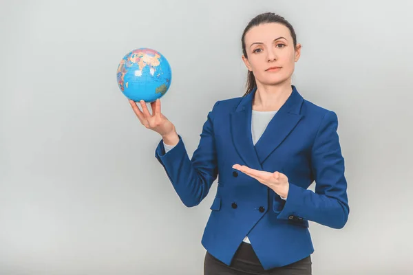 Young geography teacher holding a globe, pointing her hand at it, looking confidently at the camera. — Stock Photo, Image