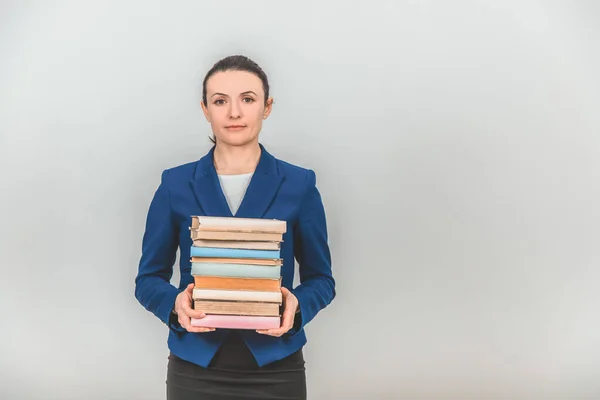 Lovely female teacher holding a stack of colorful books, looking calm and pleased. — Stock Photo, Image
