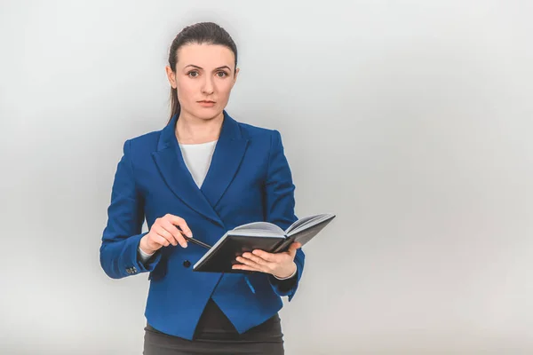 Serious teacher standing with notebook and pen in her hands, looking very strict. — Stock Photo, Image