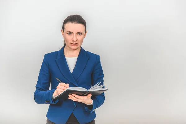 Teacher standing with notebook and pen in her hands, looking angry and irritated. — Stock Photo, Image
