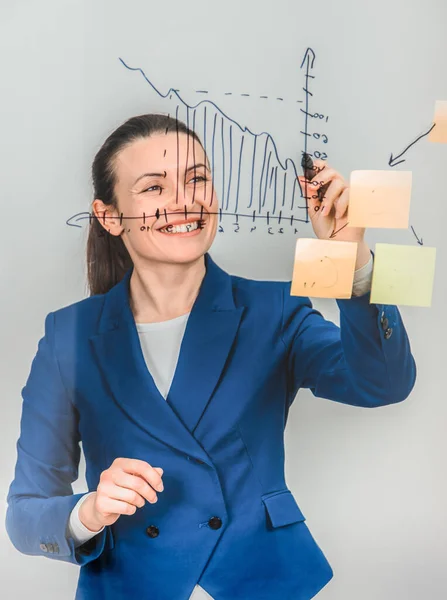 Inspired woman in formal suit, drawing diagram on the glass, smiling. — Stock Photo, Image