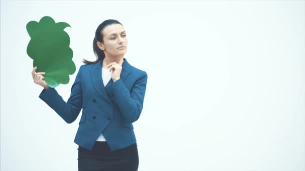 En vacker ung lärare håller en grön popup. Peka på den och le. Läraren står på en vit bakgrund. — Stockvideo