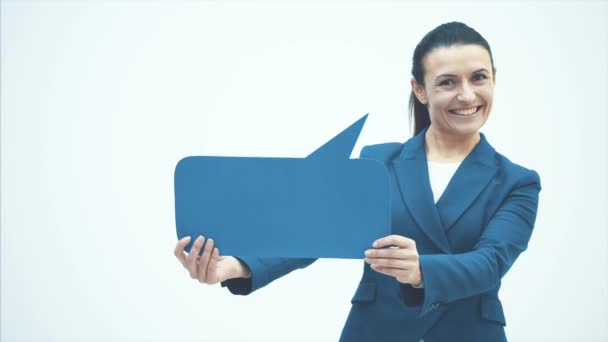 Young smiling teacher stands on a white background. Holds one hand blue speech bubble.Close up. Copy space Smirked. — ストック動画