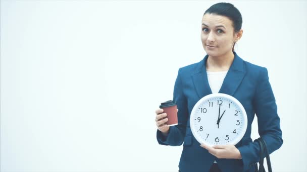 Joven buen maestro de pie sobre un fondo blanco. Tiene un reloj blanco y café. Sonrisas sinceras . — Vídeos de Stock