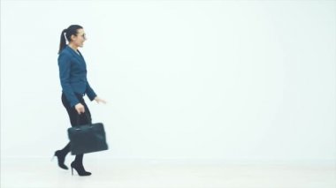 Beyaz arka planda genç ve güzel bir iş kadını modeli. Çanta beyaz bir arka planda çalışıyor. Mutlu ve enerjik bir kadın..