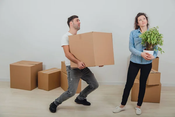 O homem não pode segurar caixas de papelão pesado mais, mas ele não sabe onde colocá-los. Sua esposa está de pé com vaso nas mãos, sonhando . — Fotografia de Stock