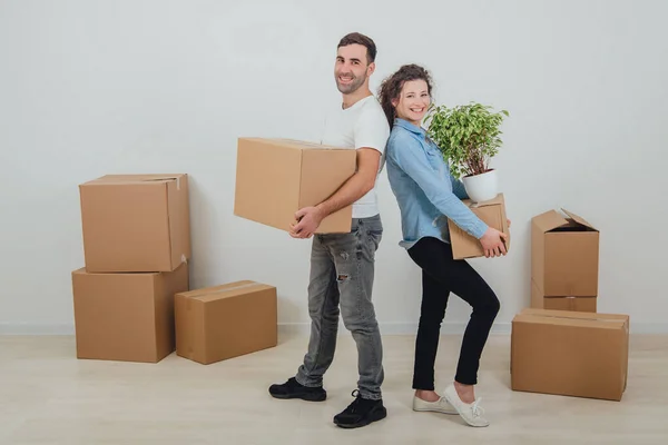 Happy wife and husband holding carton boxes, standing back to back, smiling extremely satisfied to move into new apartment. — Stock Photo, Image