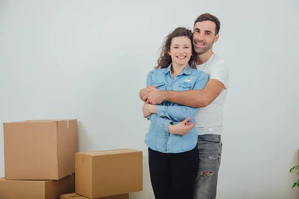 Couple moving into their new house, husband is hugging his wife,looking at the camera, smiling. — Stock Photo, Image