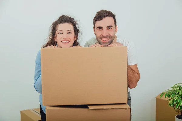Esposa engraçada e marido se escondendo atrás da grande caixa de papelão, juntos, olhando tolamente . — Fotografia de Stock