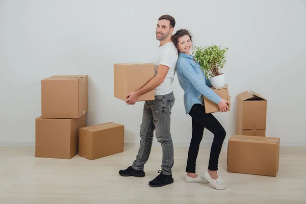 Happy wife and husband holding carton boxes, standing back to back, smiling extremely satisfied to move into new apartment. — Stock Photo, Image