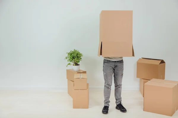 O homem engraçado está de pé com uma caixa de papelão na cabeça. Jovem bonito movendo-se para a casa nova . — Fotografia de Stock