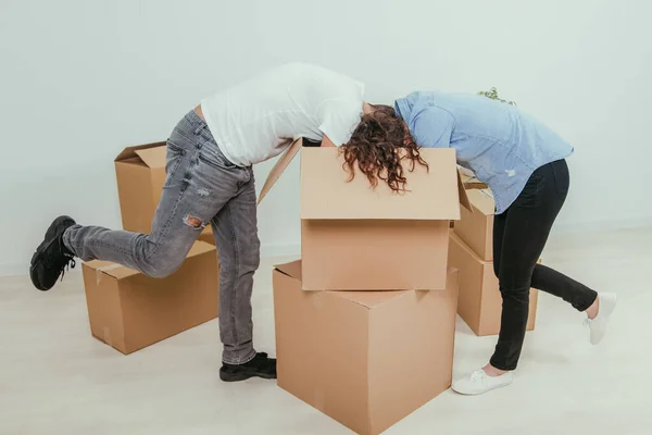 Femme et mari sont occupés, déballer les boîtes en carton. Ils sont debout en train de baisser la tête dans la grande boîte . — Photo