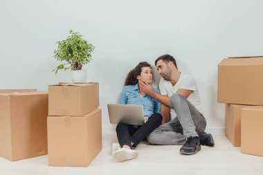 Sevimli eş üzgün. Kocası onu sakinleştiriyor. Dairede dizüstü bilgisayarı olan genç bir çift yerde oturuyor..