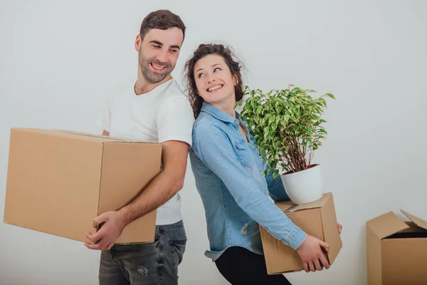 Happy wife and husband holding carton boxes, standing back to back, looking at each other, smiling, extremely satisfied to move into new apartment. — Stock Photo, Image