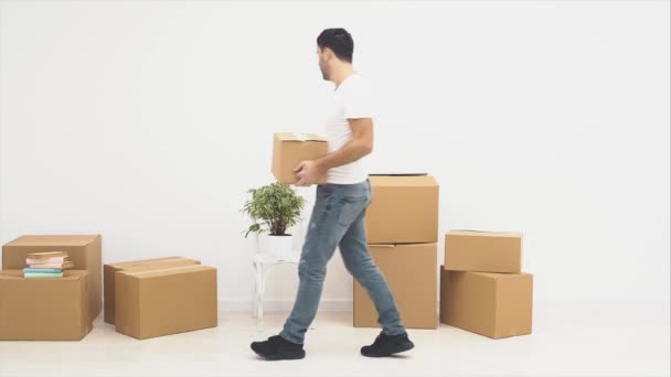 El hombre está entrando en una habitación. Lleva una caja de cartón. De repente, su esposa entra y lo está alejando. La pareja está satisfecha. Copiar espacio. 4K . — Vídeos de Stock