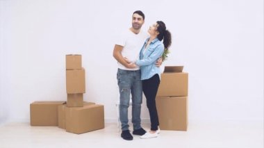 Genç çift yeni bir daireye taşındı. Kucaklaşıyorlar ve sarılıyorlar. Gülümseyen çift. Kapatın. Motor, animasyon. 4k.