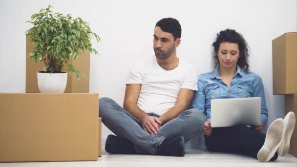 Νεαρό ζευγάρι μετακομίζει σε ένα νέο διαμέρισμα μαζί. Σκέφτονται από τι να ξεκινήσουν, κοιτάζοντας την οθόνη του laptop. Πάμε. Κινούμενα σχέδια. 4ια. — Αρχείο Βίντεο