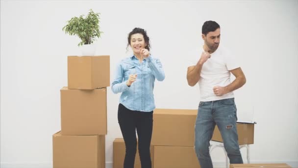 Casal jovem mudou-se para um novo apartamento juntos. Eles estão dançando e tocando o palhaço. Espaço para cópia. Acção, Animação. 4K . — Vídeo de Stock