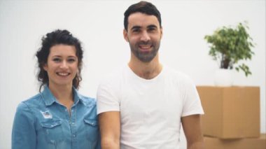 Genç çift yeni bir daireye taşındı. Kucaklaşıyorlar ve sarılıyorlar. Çift etrafa bakıyor. Uzayı kopyala Arka plan bulanık. Motor, animasyon. 4k.