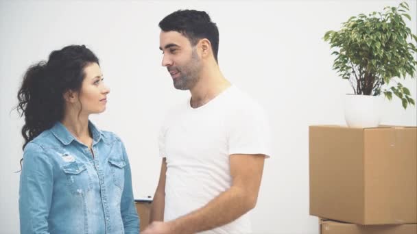 Una joven pareja se mudó a un nuevo apartamento juntos. Se están abrazando y acurrucándose. Una pareja está mirando a su alrededor. Copiar espacio. Acción, animación. 4K . — Vídeos de Stock