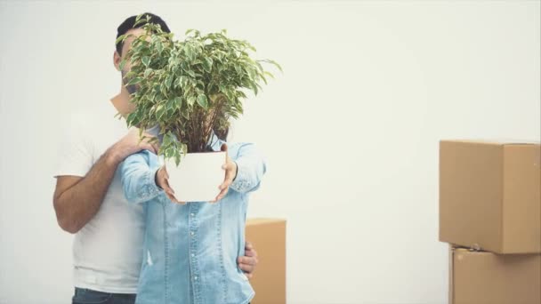 Young couple moved to a new apartment together. They are holding a green flowerpot and smiling. Action, Animation. 4K. — Stock Video