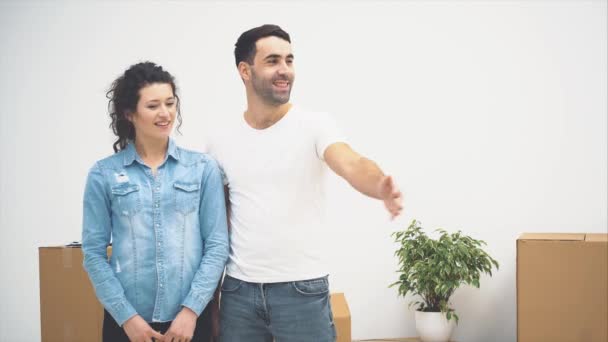 Una joven pareja se mudó a un nuevo apartamento juntos. Se están abrazando y acurrucándose. Una pareja está mirando a su alrededor. Copiar espacio. Acción, animación. 4K . — Vídeos de Stock