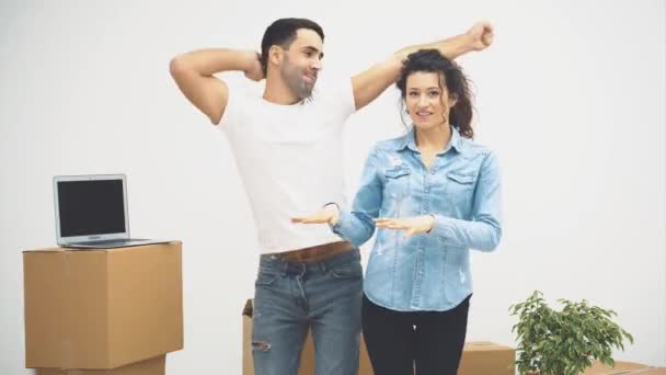 Jeune couple a déménagé dans un nouvel appartement ensemble. Ils dansent et jouent au bouffon. Le couple regarde autour de lui. Espace de copie. Action, animation. 4K . — Video