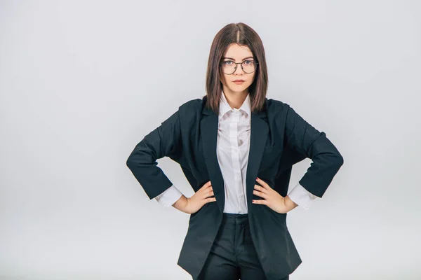 Young confident businesswoman in black suit standing, keeping her hands akimbo, looking at the camera suspiciously. — Stock Photo, Image