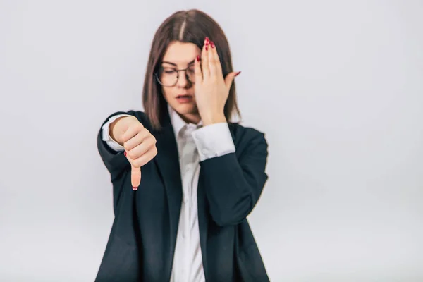 Blurred lovely young businesswoman in black suit standing, giving thumbs down, keeping hand on the head, eyes closed. Focus on the gesture. — Stock Photo, Image