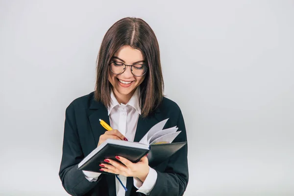 Pretty young businesslady in black suit standing, listening attentively, noting something in her notebook. — Stock Photo, Image