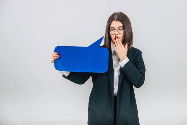 Portrait of an excited young business woman holding empty square blue speech bubble, covering her mouth with hand, surprised face. — Stock Photo, Image